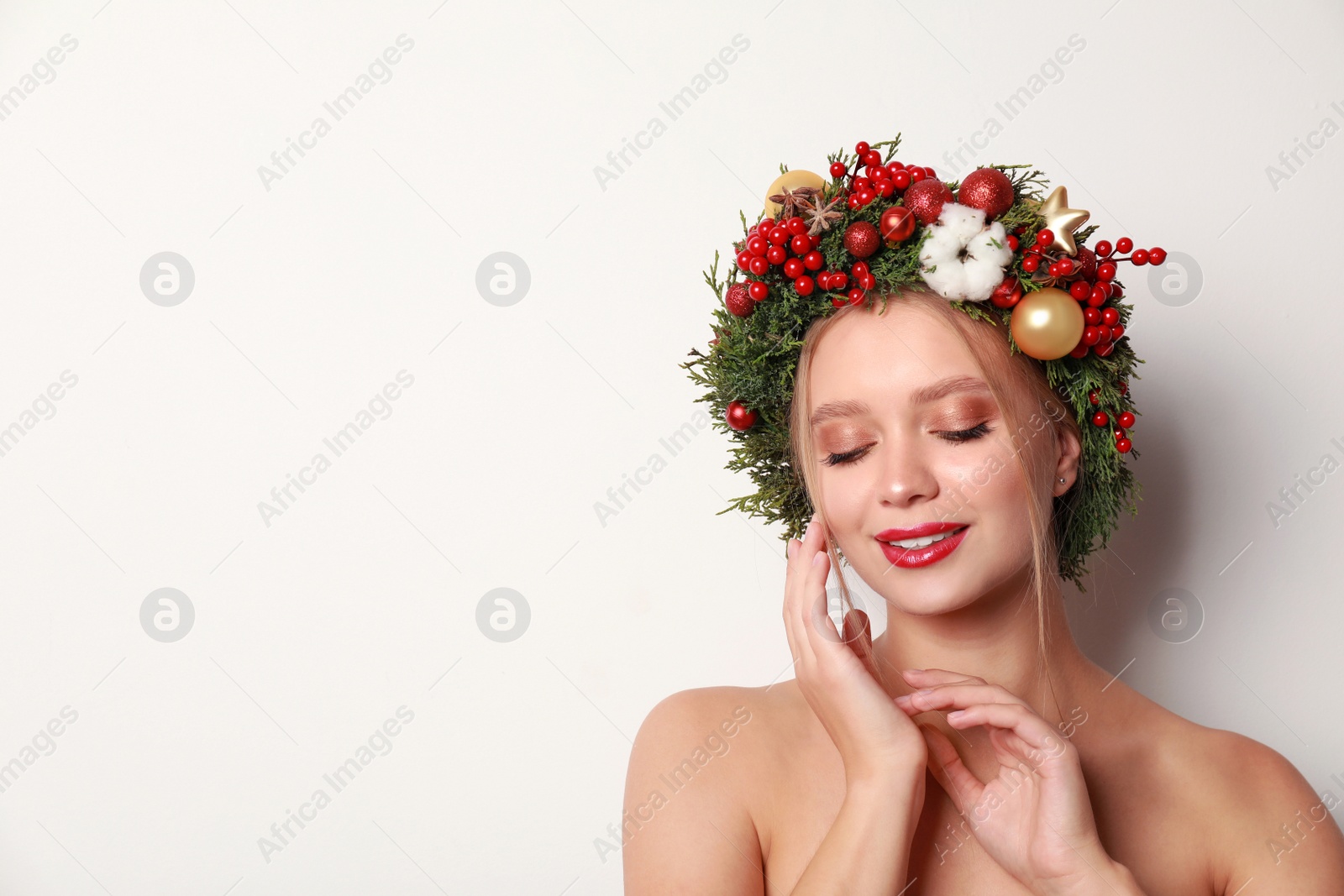 Photo of Beautiful young woman wearing Christmas wreath on white background. Space for text