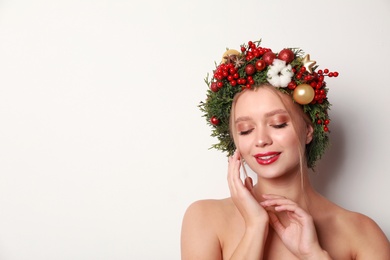 Photo of Beautiful young woman wearing Christmas wreath on white background. Space for text