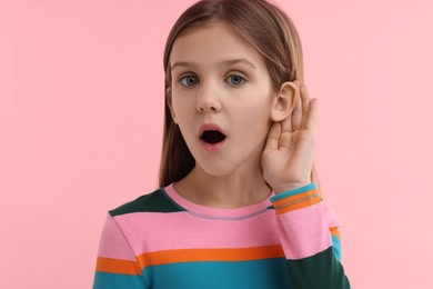 Little girl with hearing problem on pink background