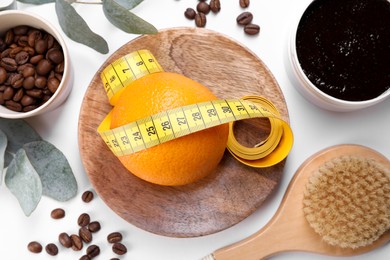 Flat lay composition with orange and measuring tape on white background. Cellulite treatment