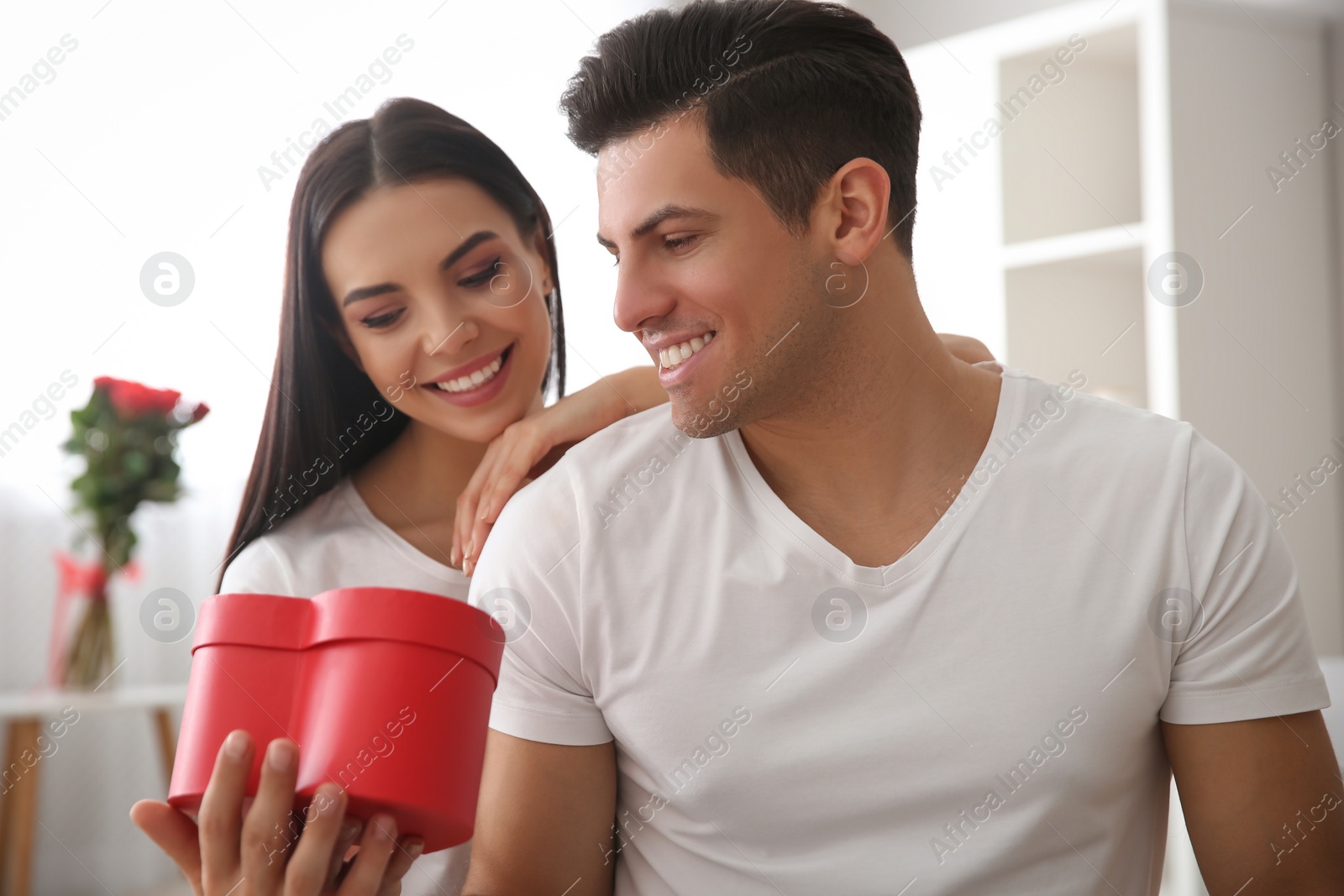 Photo of Lovely couple with gift box at home. Valentine's day celebration