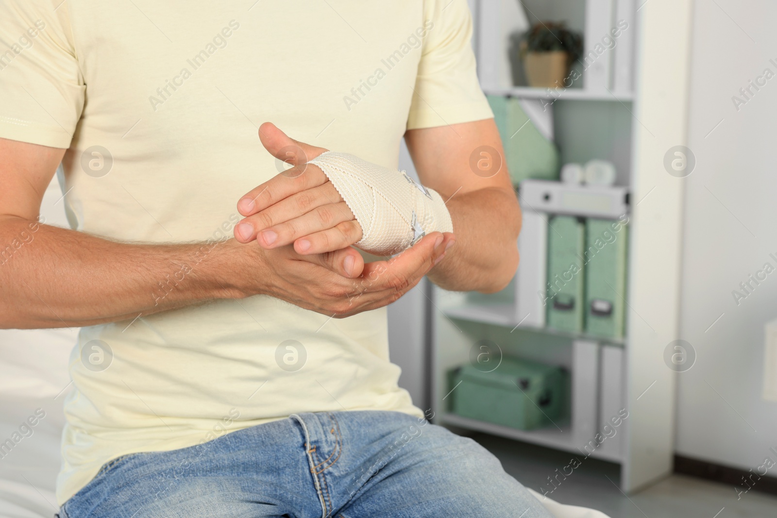 Photo of Man with hand wrapped in medical bandage at hospital, closeup. Space for text