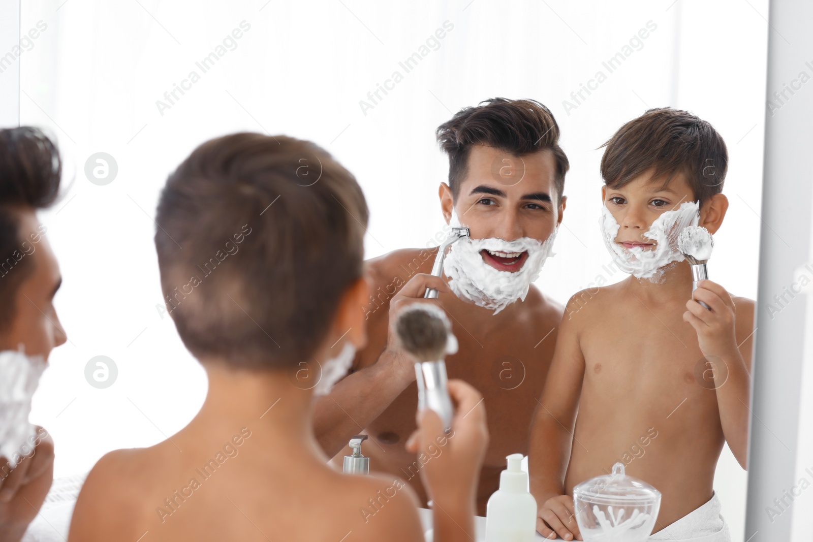 Photo of Father and son having fun while shaving in bathroom