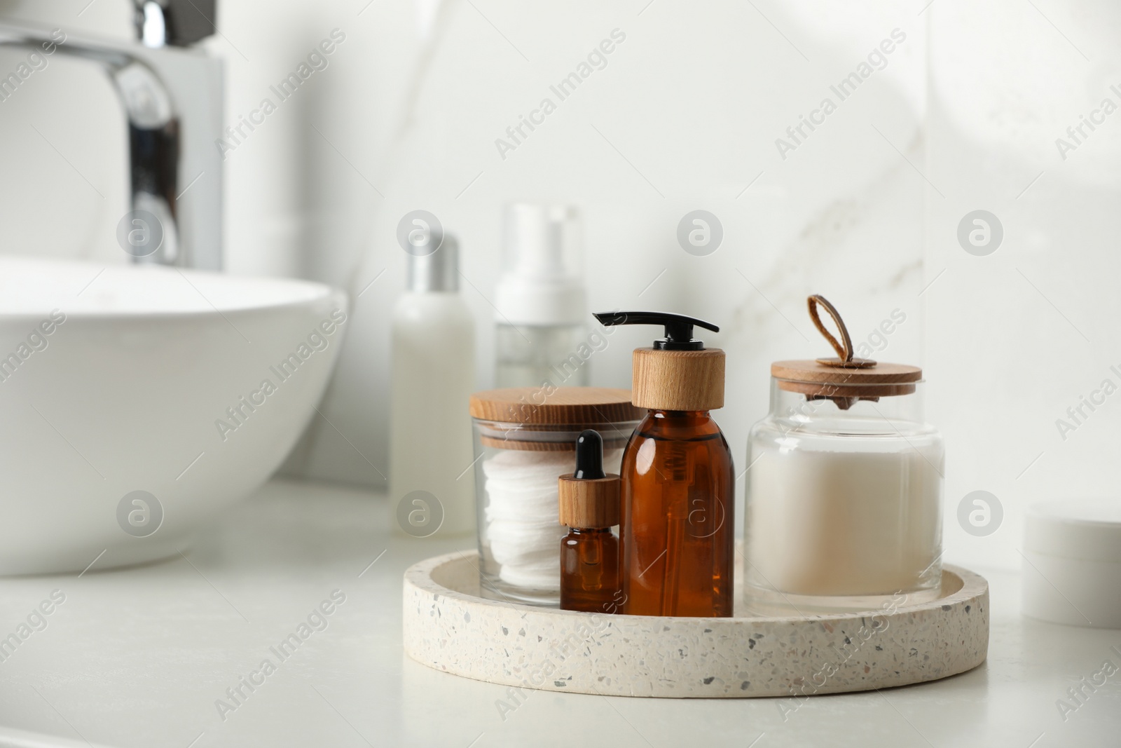 Photo of Tray with dispenser bottle and cosmetic products on white table in bathroom