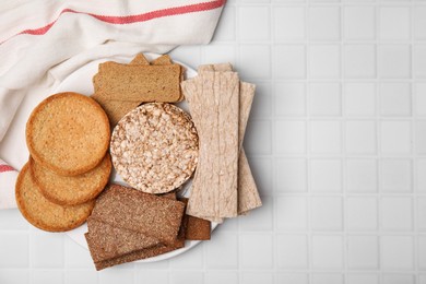 Rye crispbreads, rice cakes and rusks on white checkered table, flat lay. Space for text
