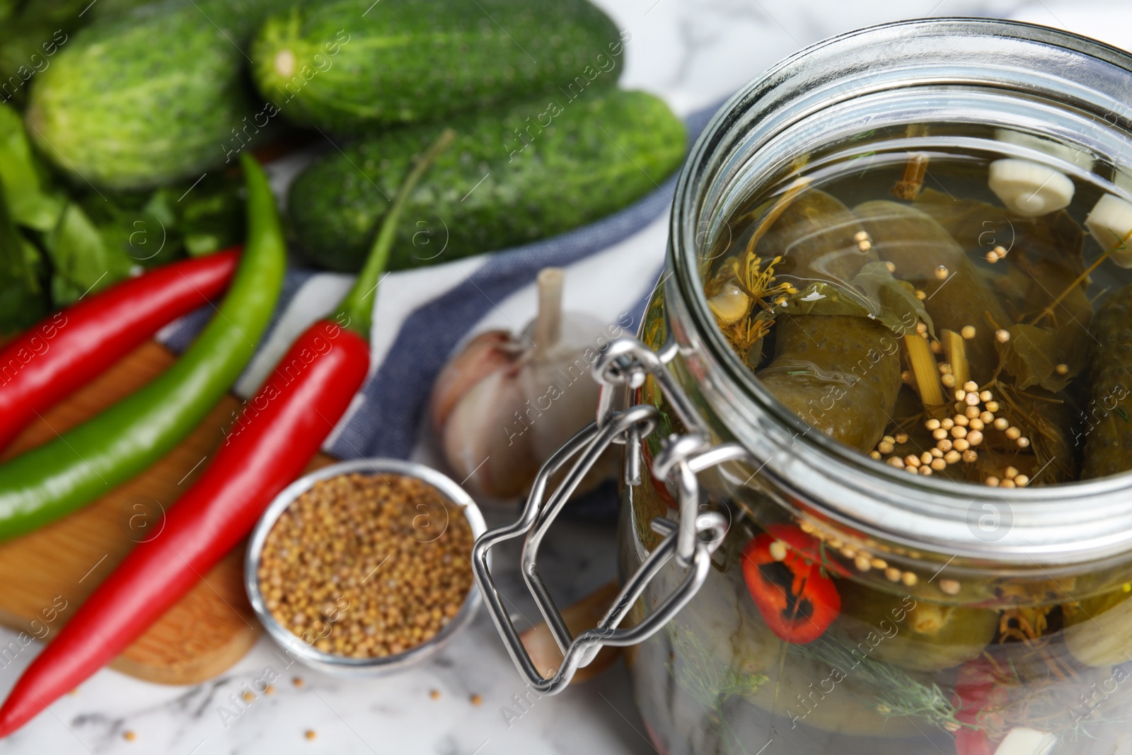 Photo of Jar with pickled cucumbers on marble table, closeup view