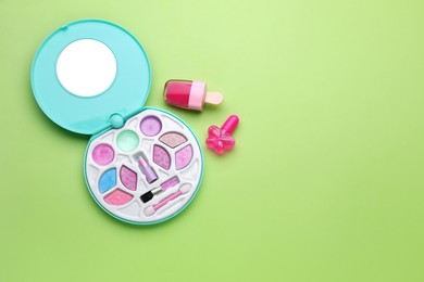 Photo of Eye shadow palette and other decorative cosmetics for kids on light green background, flat lay. Space for text