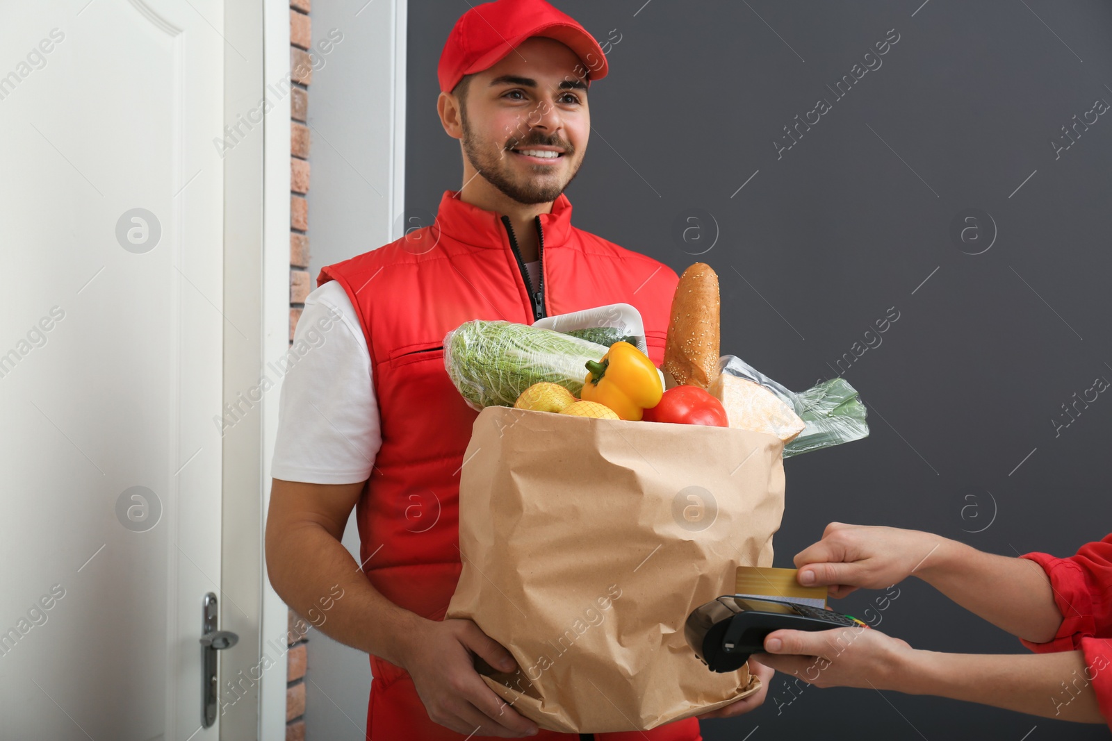 Photo of Woman using terminal to pay for food delivery indoors