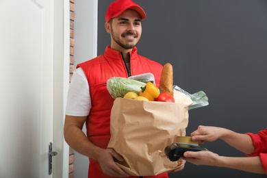 Woman using terminal to pay for food delivery indoors