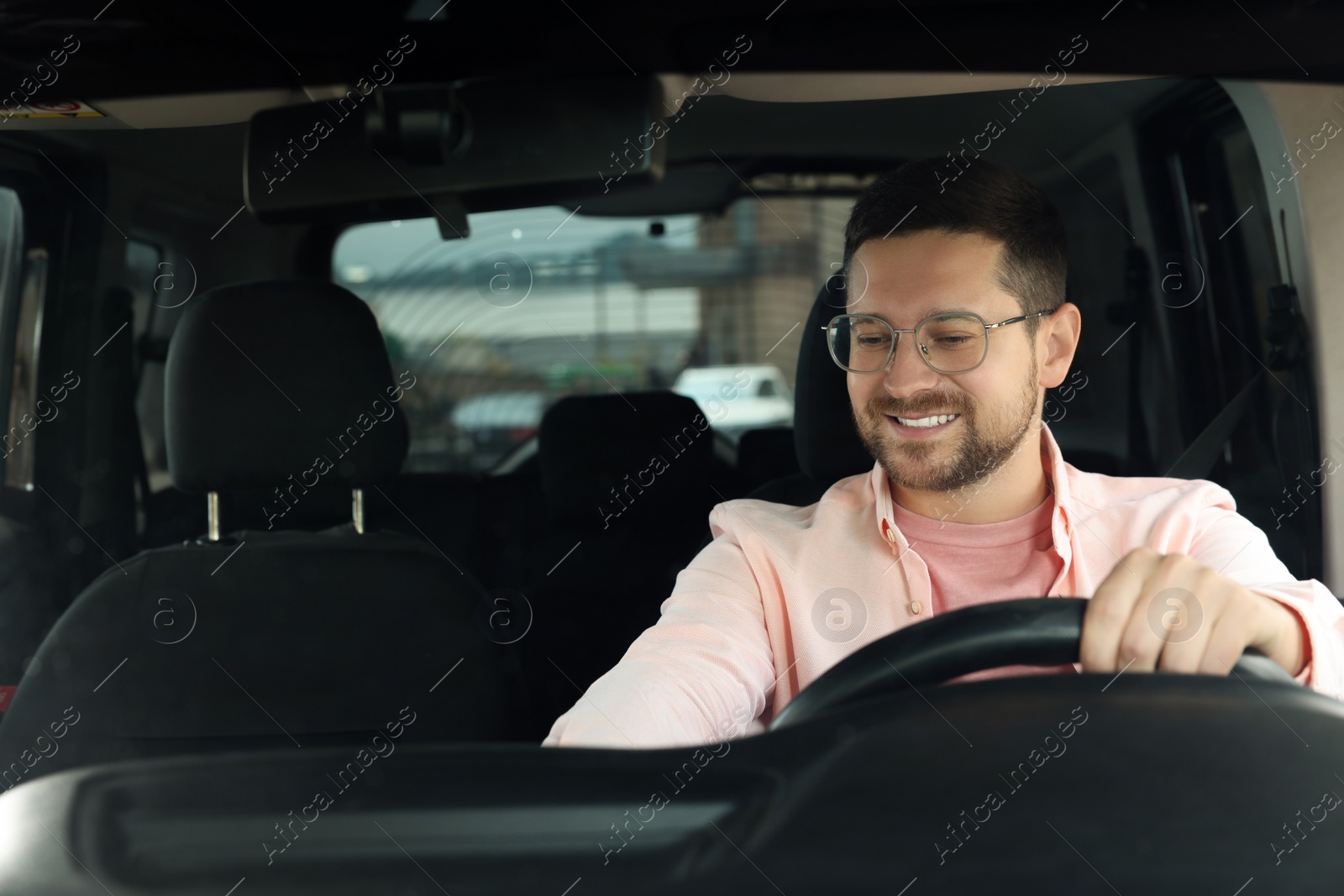 Photo of Listening to radio. Handsome man enjoying music in car, view through windshield