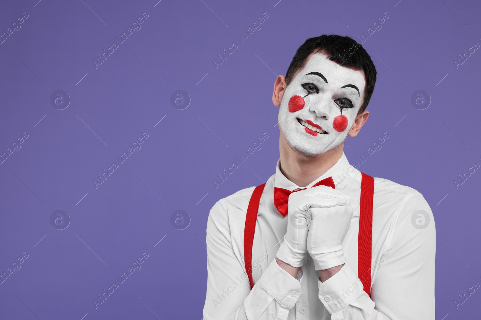 Photo of Funny mime artist posing on purple background. Space for text