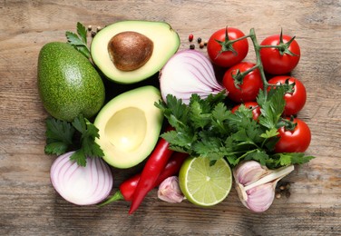 Photo of Fresh ingredients for guacamole on wooden table, flat lay