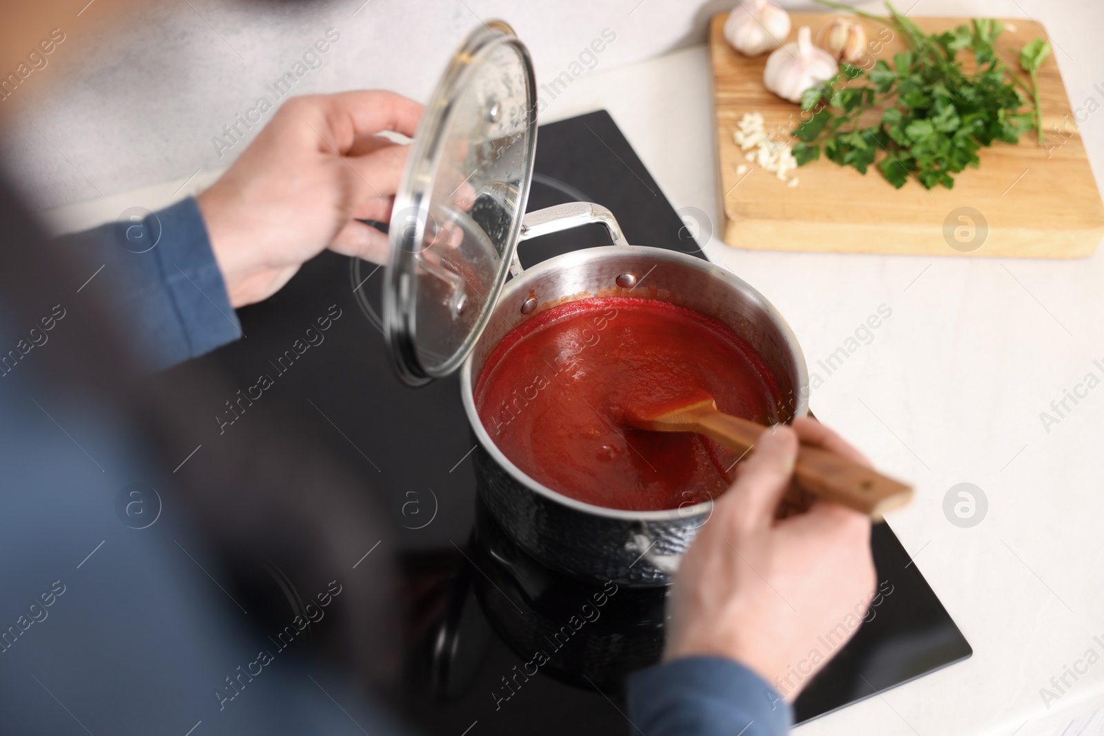 Photo of Man cooking tomato soup on cooktop, above view