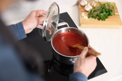 Man cooking tomato soup on cooktop, above view