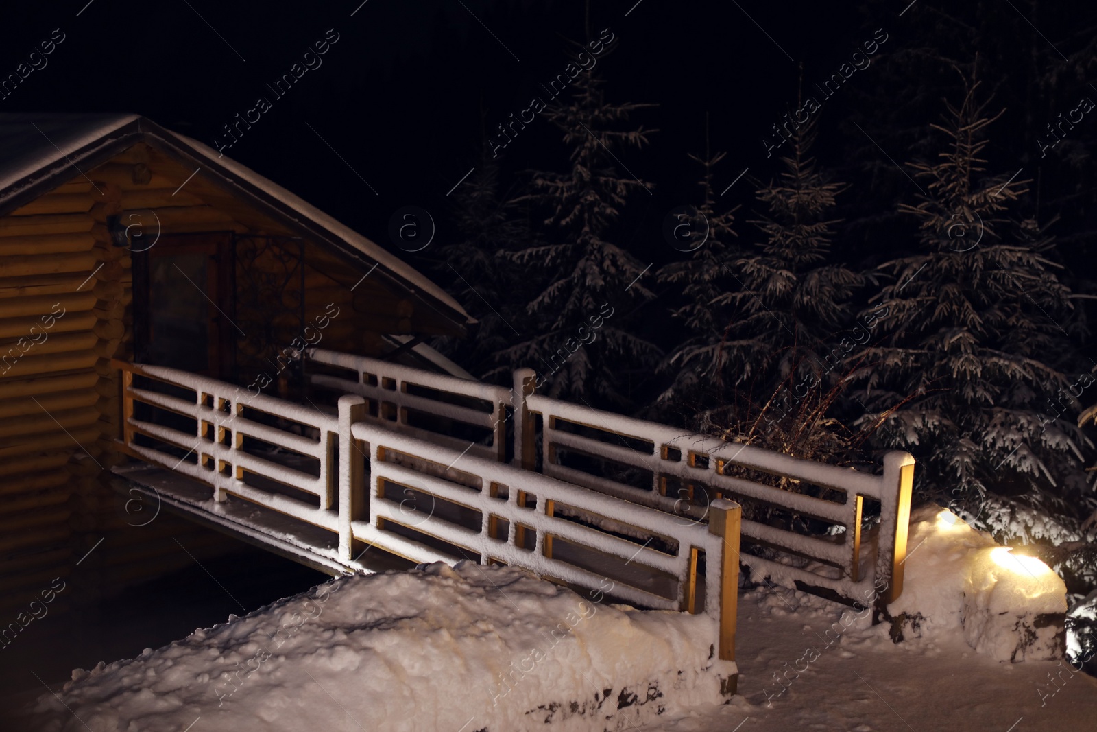 Photo of Wooden cottage near snowy forest at evening