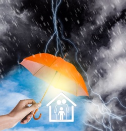 Image of Insurance concept. Woman covering illustration with orange umbrella during storm, closeup