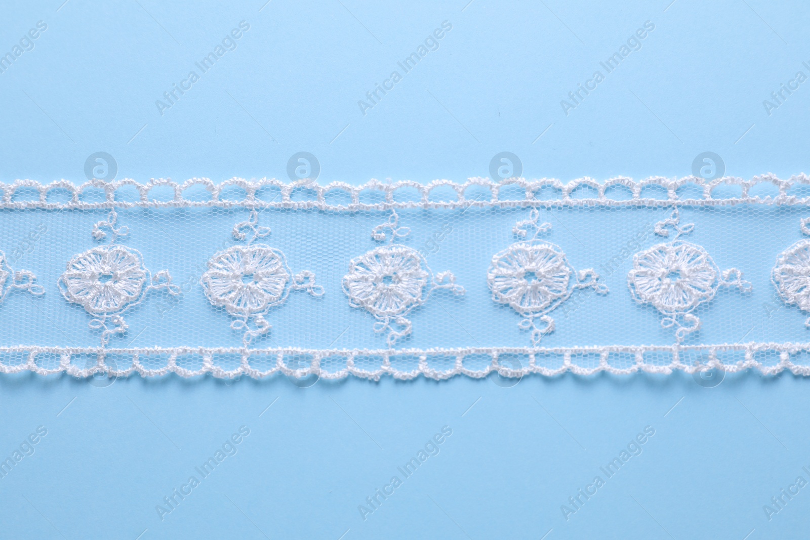 Photo of White lace on light blue background, top view