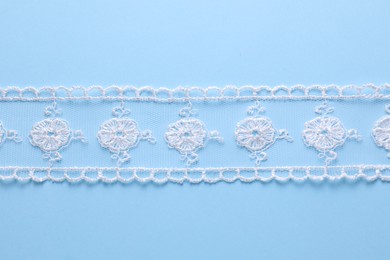 Photo of White lace on light blue background, top view