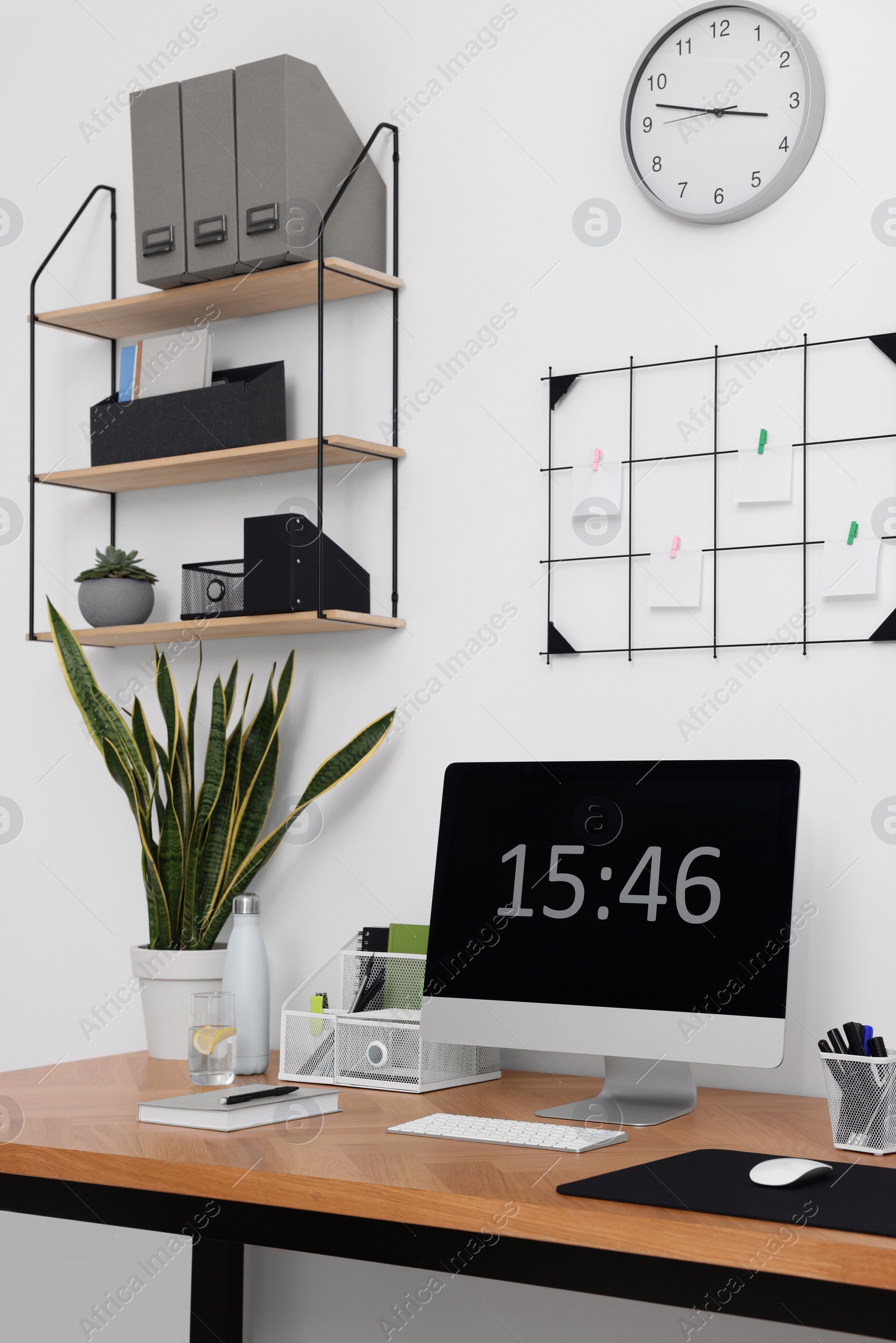 Photo of Cozy workplace with computer, modern furniture and houseplants at home