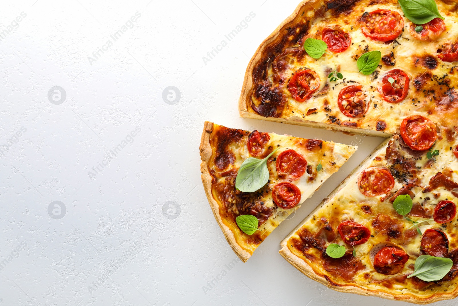 Photo of Cut delicious homemade quiche with prosciutto on white background, top view. Space for text