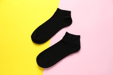 Photo of Pair of black socks on colorful background, flat lay
