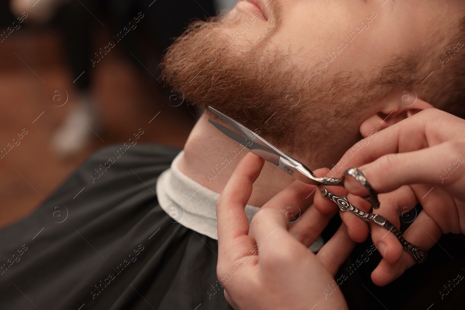 Photo of Professional hairdresser working with bearded client in barbershop, closeup