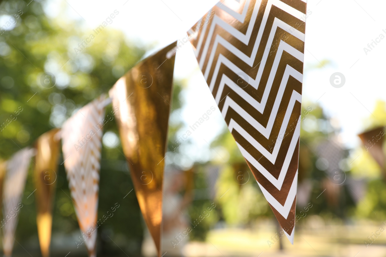 Photo of Golden bunting flags in park. Party decor