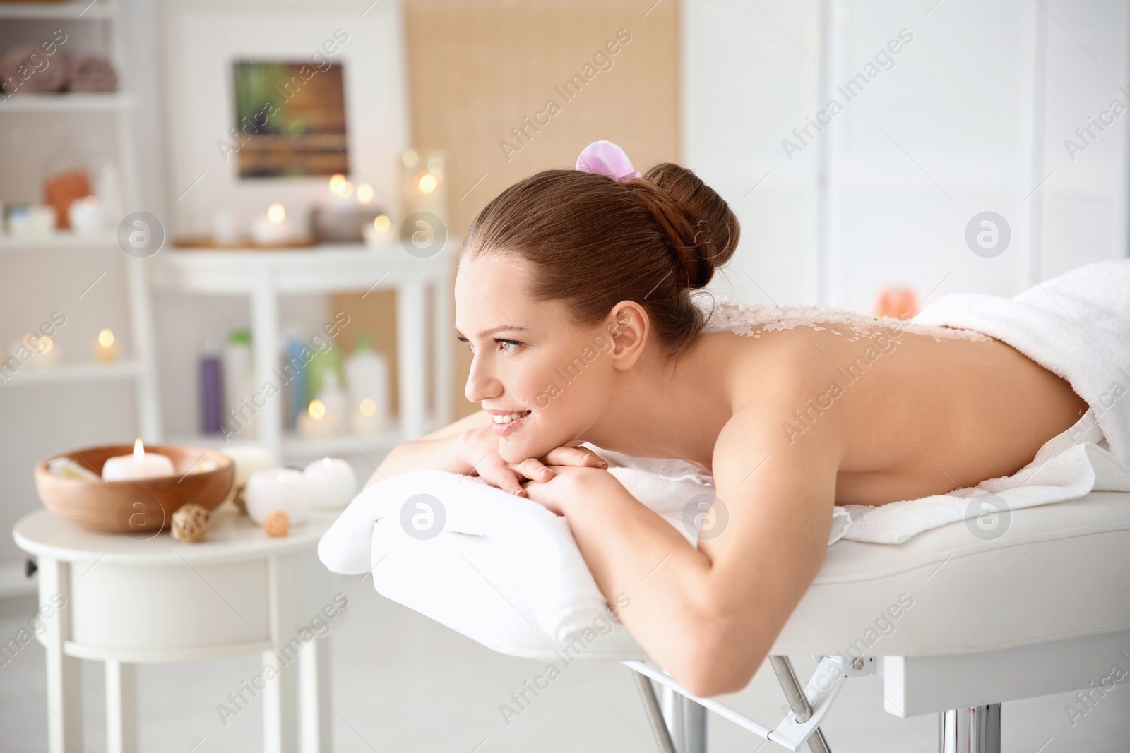 Photo of Beautiful young woman having massage with body scrub in spa salon