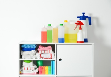 Photo of Cabinet with different cleaning supplies on white background