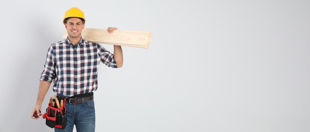 Handsome carpenter with wooden planks on light background, space for text. Banner design