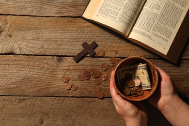 Photo of Donate and give concept. Woman with bowl of money. Bible and cross on wooden table, top view with space for text