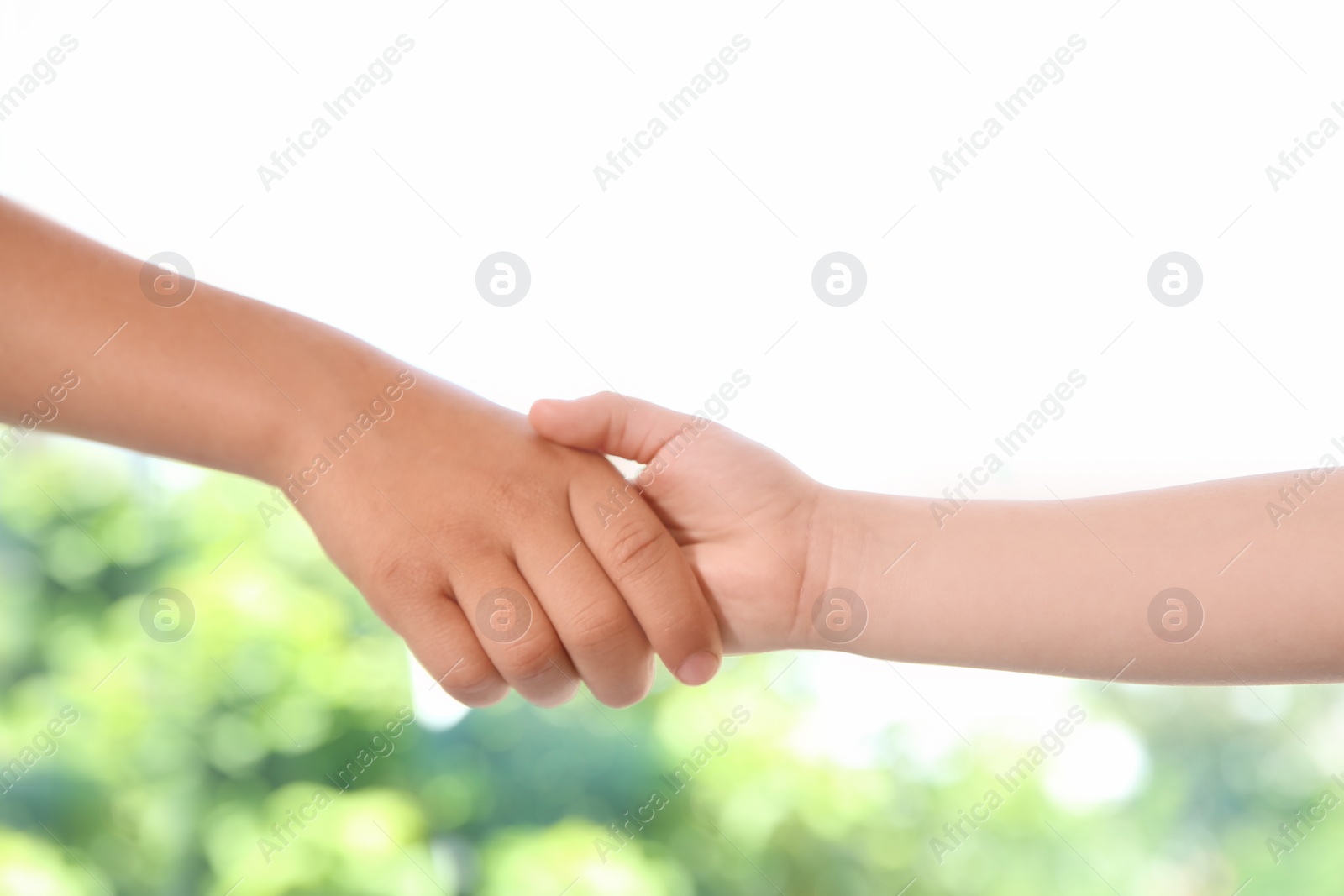Photo of Children holding hands on blurred background, closeup. Unity concept