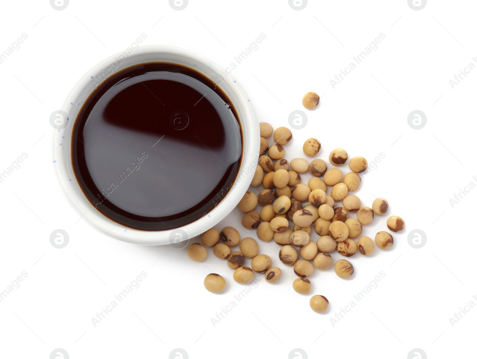 Photo of Tasty soy sauce in bowl and soybeans isolated on white, top view