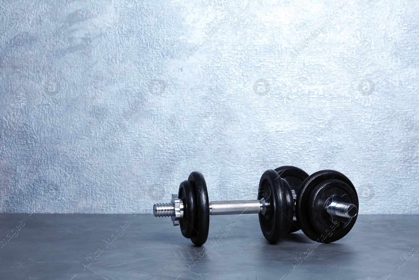 Photo of Pair of adjustable dumbbells on floor near color wall. Space for text