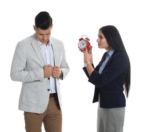 Businesswoman with alarm clock scolding employee for being late on white background