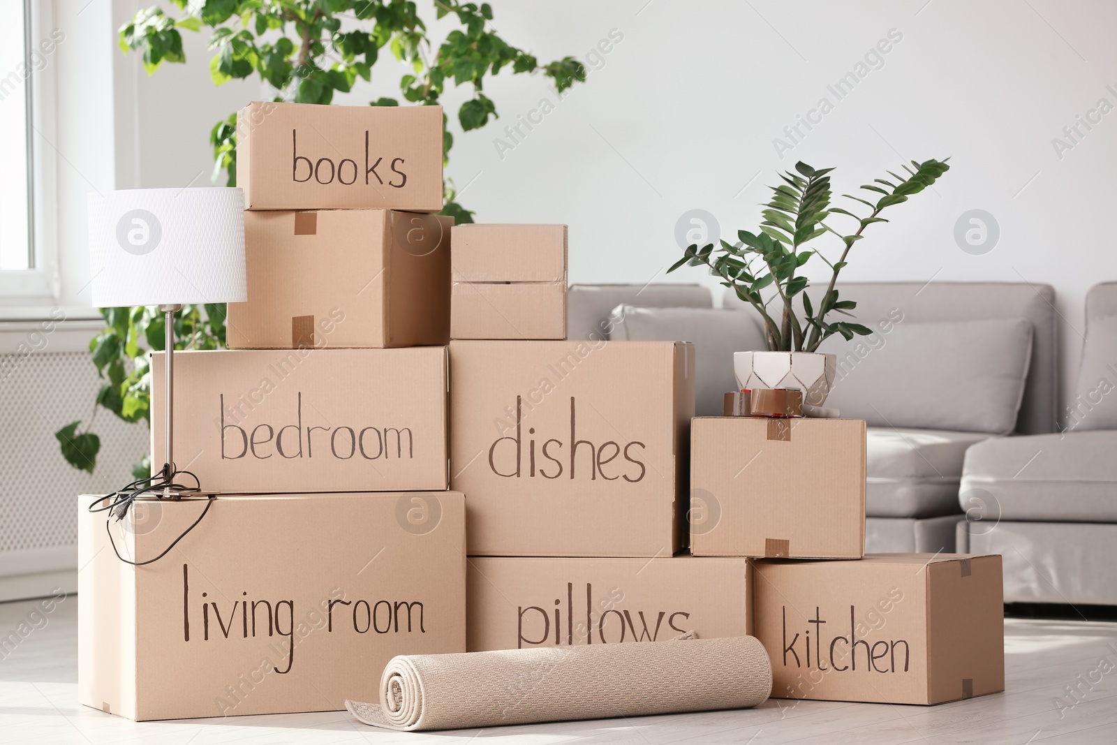 Photo of Pile of moving boxes and household stuff in living room