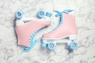 Photo of Pair of stylish quad roller skates on marble background, top view