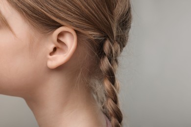 Photo of Hearing problem. Little girl on grey background, closeup of ear. Space for text