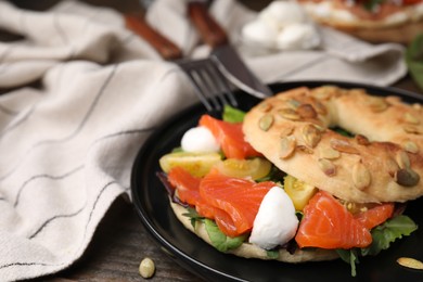 Photo of Tasty bagel with salmon, mozzarella cheese, tomatoes and lettuce on table, closeup. Space for text