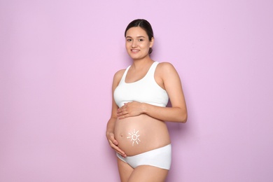 Photo of Sun painted with body cream on pregnant woman's belly against color background