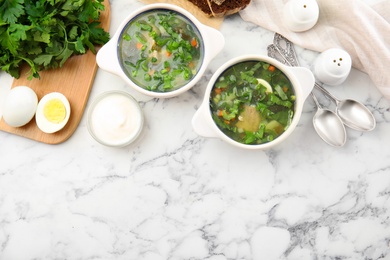 Photo of Delicious sorrel soup served on white marble table, flat lay. Space for text