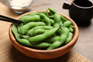 Photo of Green edamame beans in pods served on wooden table