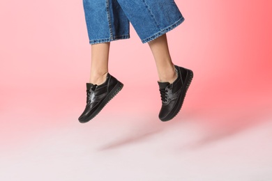 Woman in stylish shoes jumping on color background, closeup