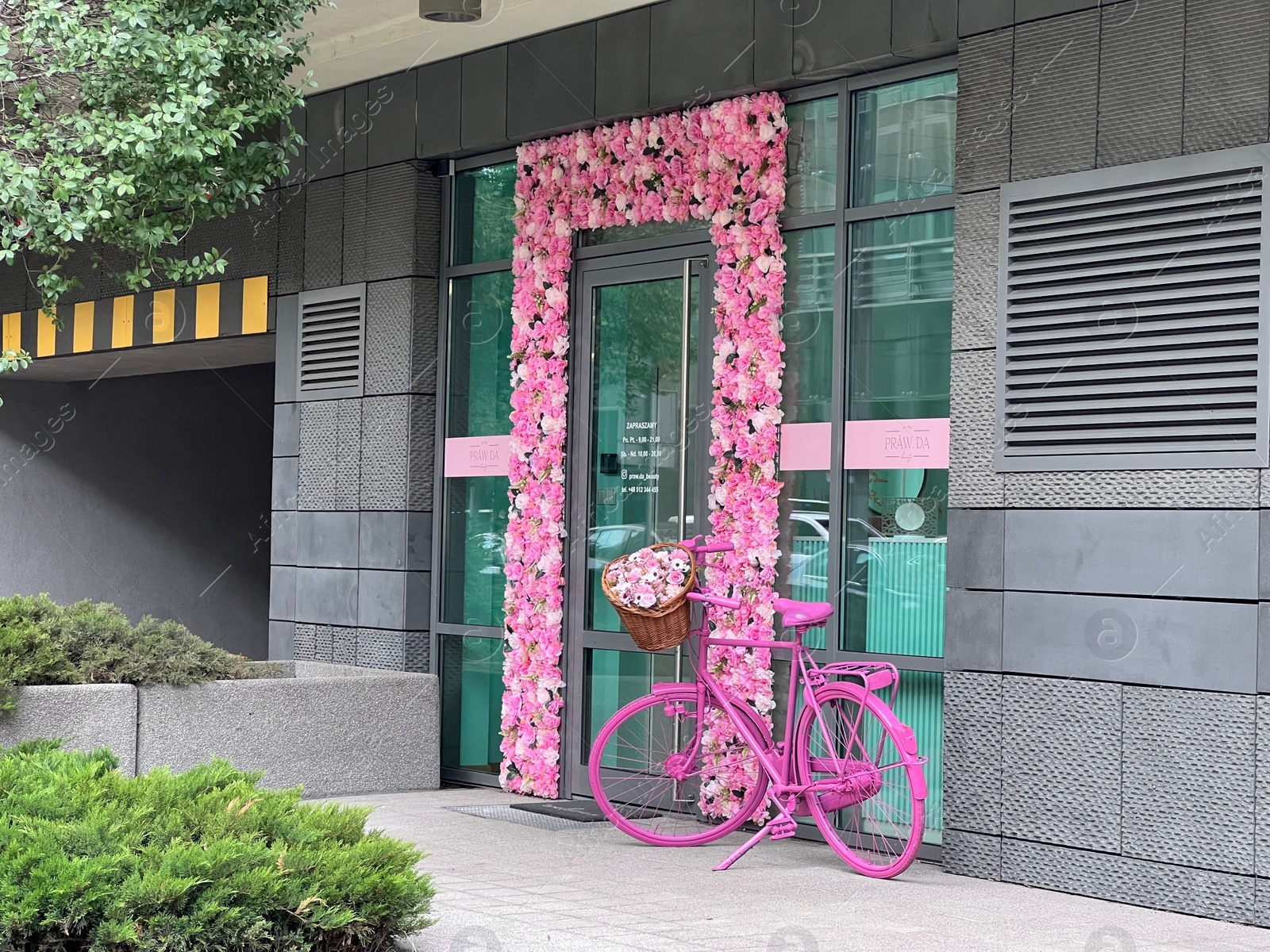 Photo of WARSAW, POLAND - JULY 13, 2022: Entrance of building decorated beautiful flowers and pink bicycle
