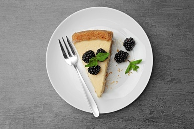 Piece of delicious cheesecake with blackberries on grey background, top view