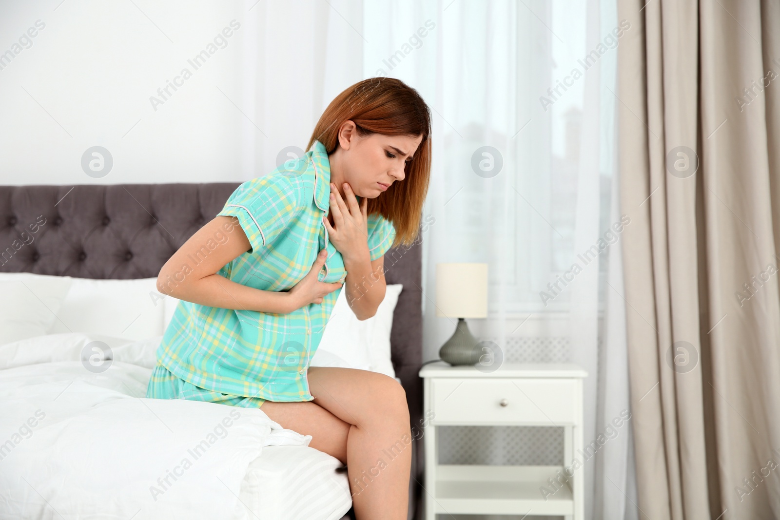 Photo of Young pregnant woman suffering from morning sickness at home. Space for text