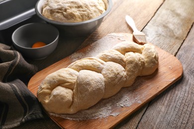 Photo of Homemade braided bread and ingredients on wooden table, above view. Cooking traditional Shabbat challah