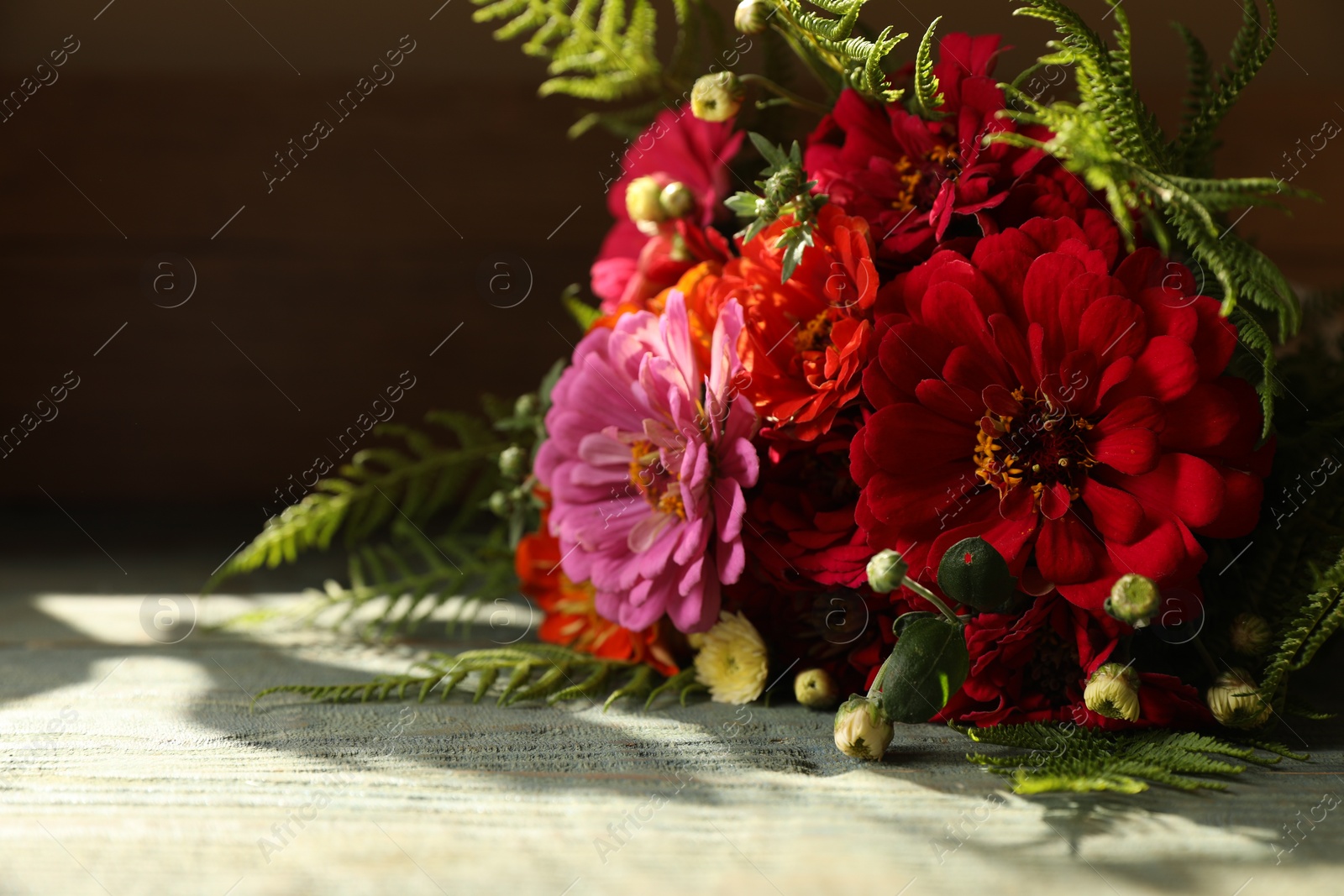 Photo of Bouquet of beautiful wild flowers on wooden rustic table against dark background. Space for text