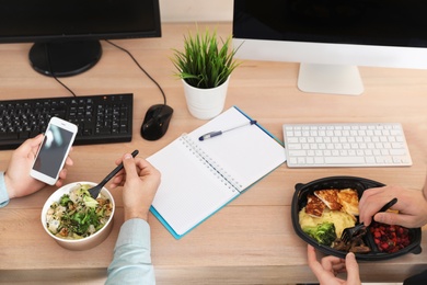 Office employees having lunch at workplace. Food delivery