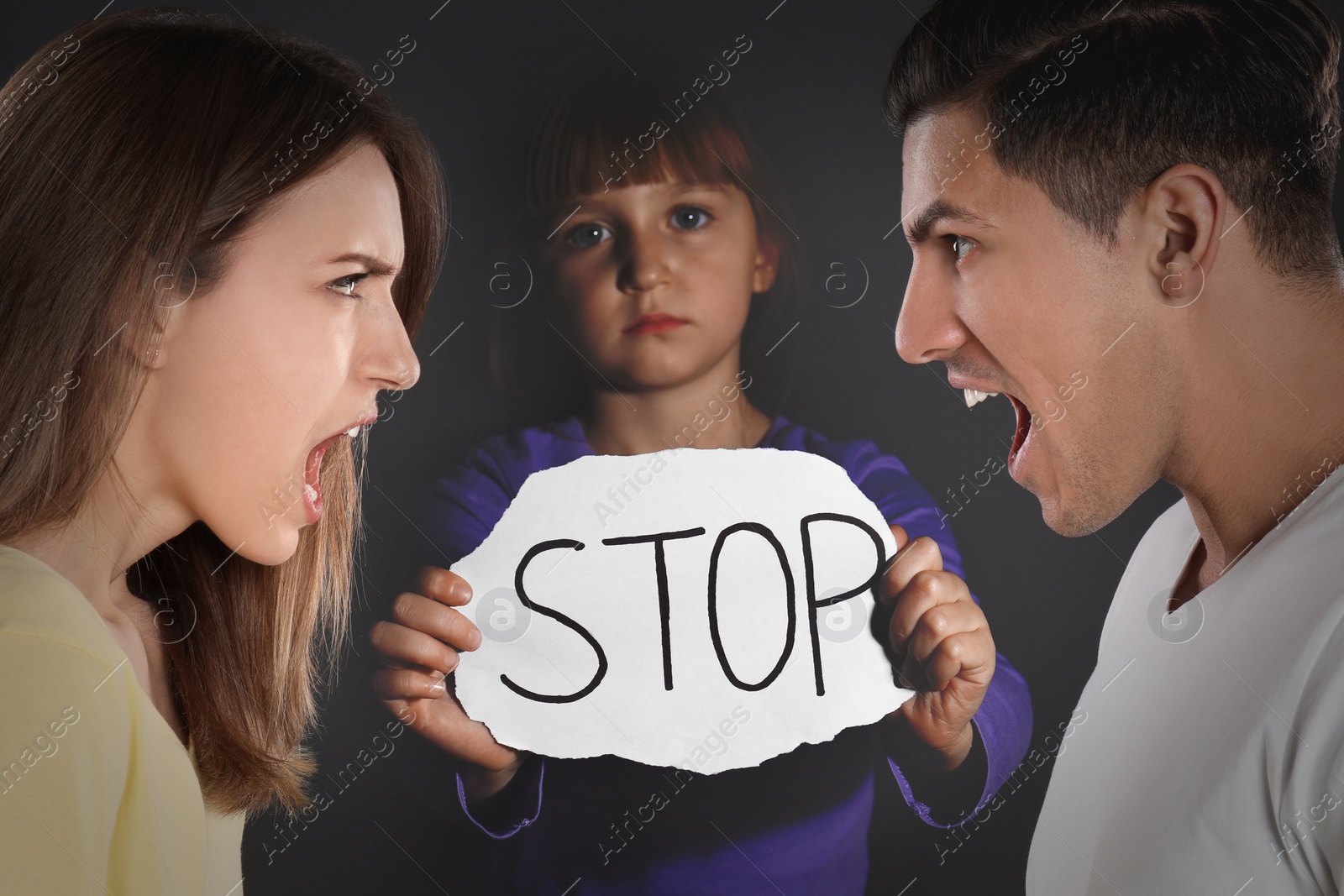 Image of Double exposure of sad little girl with sign STOP and her arguing parents